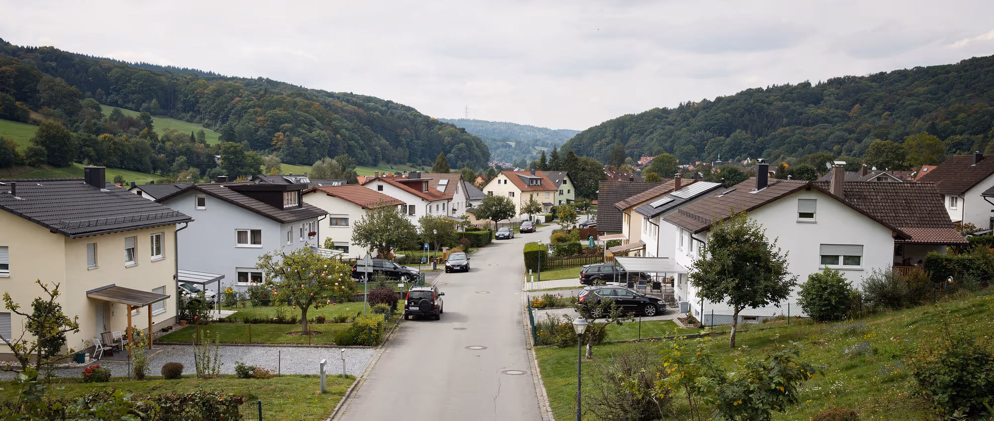 Ortsansicht von Blaustein im Blautal westlich von Ulm mit Einfamilienhäusern am Hang und bewaldeten Hügeln